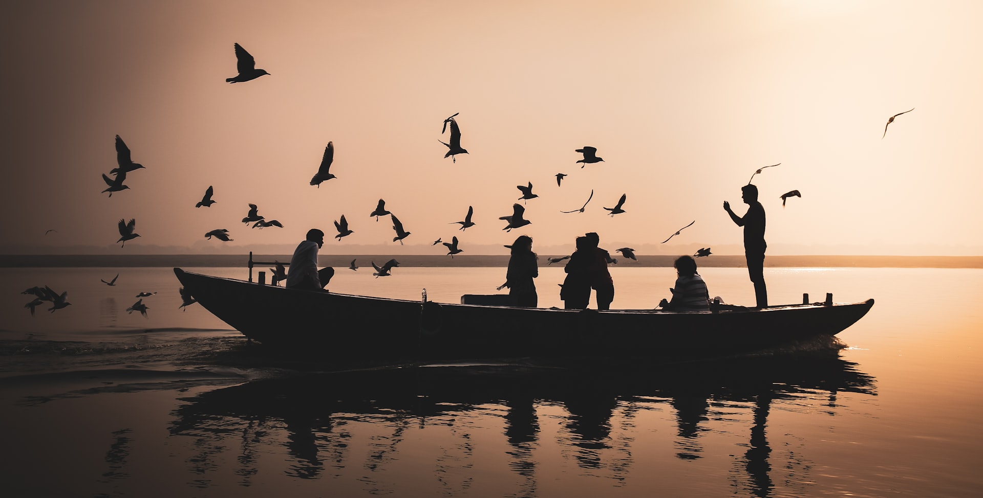 silhouette of people riding on boat during sunset